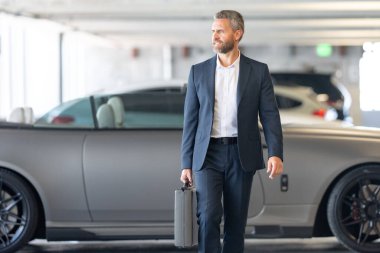 Zengin bir iş adamı pahalı lüks bir arabada. Takım elbiseli zengin bir iş adamı. Şehirdeki başarılı zengin iş adamı. Kendine güvenen bir iş adamı. Başarı işi. İş adamı sokakta yürüyor