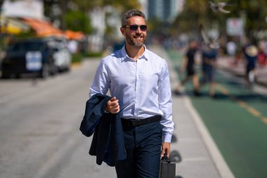 İş adamı kentte güvenle yürüyor. Sokakta yürüyen bir iş adamı. Ofise doğru yürüyen yakışıklı bir iş adamı. Kendine güvenen girişimci iş adamı dışarıda dolaşıyor.