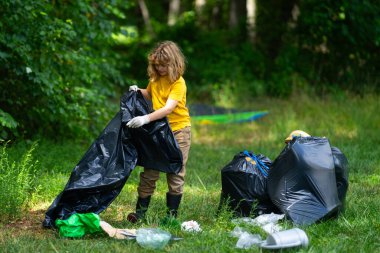 Çocuk doğayı temizlemek için plastik çöp topluyor. Çocuk dışarıdaki çöpleri temizliyor. Ekoloji konsepti. Çevre Günü. Dünyayı kurtar. Çöp geri dönüşüm çöpü. Ekoloji. Çevresel bakım. Eko çocuk