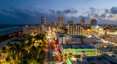 Miami Sahili Günbatımı hava manzarası. Alacakaranlıkta Miami 'nin göbeğinde. Güney Sahili neon ışıkları. Tropik Miami kıyısı manzarası. Ocean Drive Art Deco binaları. Miami kıyı şeridinin havadan görüntüsü