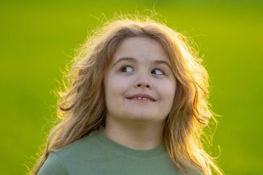 Çocuğun yakın plan portresi başka yere bakıyor. Çocuk suratı. Mutlu bir çocuğun yaz portresi başka yere bakıyor. Çocuk yüzü parkta başka yere bakıyor. Dışarıdaki neşeli çocuğun sevimli yüzü. Çocuğun eğlenceli yüzü başka yere bakıyor.