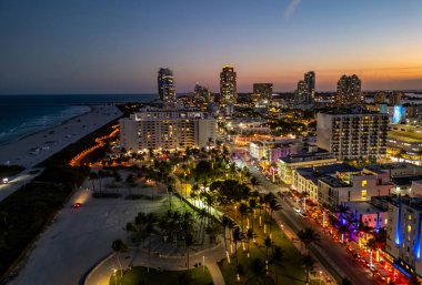 Okyanus manzaralı Miami silueti. Güney Florida sahillerinde gün batımı. Şehrin insansız hava aracı görüntüsü. Geceleri Miami 'nin gökyüzünü aydınlatırdı. Miami rıhtımının panoramik gecesi. Miami Sahili 'nin ünlü simgeleri
