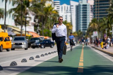 İş adamı işe yürüyerek gider. Hispanik iş adamı sokakta güven içinde yürüyor. Ofis çalışanı ofise gidiyor. Olgun bir iş adamı şehirde yürüyor. Dışarıda dolaşan gömlekli bir iş adamı.