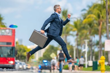 İş atlayışı. Caddeye atlayan komik iş adamı. Takım elbiseli bir işadamı geç kaldı ve atladı. Sıçrama hareketiyle meşgul bir iş adamı. Kendine güvenen işadamı heyecanla zıplıyor.