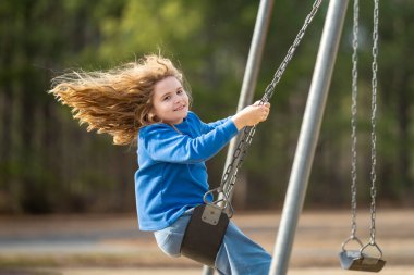Çocuk salıncakta eğleniyor. Çocuk bahçesinde mutlu bir çocuk. Havada sallanan kaygısız çocuk. Mutlu çocuklar dışarıda oynuyor. Sarışın çocuk heyecandan titriyor. Dışarıdaki oyuncu çocuk. Komik çocuk suratı
