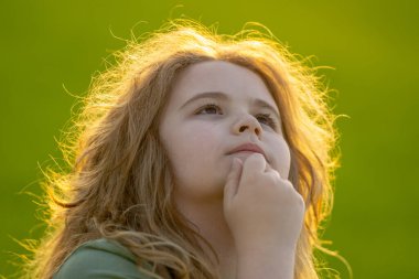 Çocuk başka tarafa bakıyor ve düşünüyor. Çocuk hayalperesti şüpheli bir bakışla düşünüyor. Derin düşünen bir çocuğun portresi. Hayalperest ergen çocuk düşüncelere daldı. Düşünceli yüzlü zeki çocuk. Hayal kuran çocuk