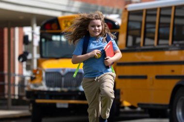 Okula dönelim. Genç öğrenciler için okul başlıyor. Okul otobüsünün yanında sırt çantalı bir çocuk. Çocuk okula gidiyor. Çocuk derse gidiyor. Okul çocuğu.