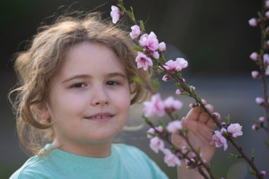 Bahar çocuk portresi. Çiçekli bir çayırdaki sarışın çocuk. Doğadaki çocukluk sevinci. Bahar günü çiçekli bir çocuk. Gülümseyen çocuk bahar doğasında açık havada oynuyor. Rüya gibi bahar çocuğu yüzü