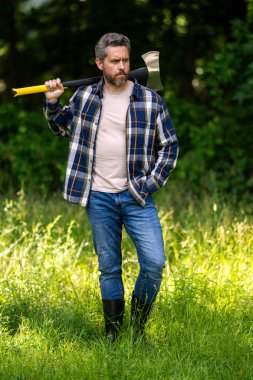 Erkek gücü. Kaslı seksi oduncu. Ağaç kesme konsepti. Ormanda kereste işçisi. Ormanda baltayla oduncu. Vahşi sakallı baltalı oduncu.