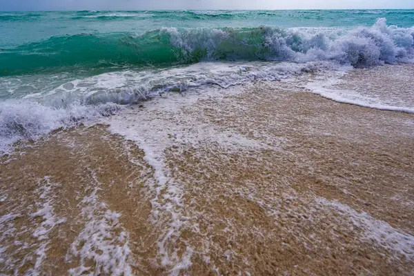 Deniz arka planı. Mavi okyanus. Kumlu okyanus plajı. Okyanus dalgaları. Yaz mevsimi. Tropik okyanus kıyısı. Egzotik turkuaz su. Köpüklü dalga denize sıçrıyor. Güneşli sahil manzarası