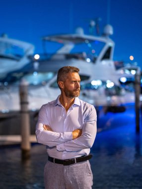 Yatın yanındaki zengin adam. Zengin milyoner adam lüks yaşam tarzının tadını çıkarıyor. Özel bir yatta milyoner bir adam. Finansal özgürlük. Zengin bir adamla pahalı bir yat. VIP premium lüks elit konsept