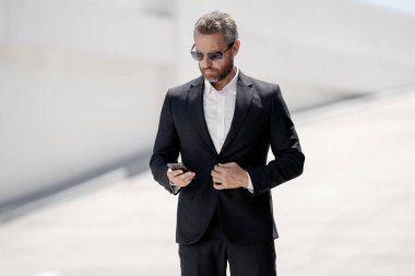 İş portresi. Dışarıdaki telefondan iş adamı aradı. Başarılı bir lider. Takım elbiseli bir adam dışarıda telefonla konuşuyor. İş adamı telefonu tut. Telefon kullanan bir iş adamı. İş başarısı. İnternet işi