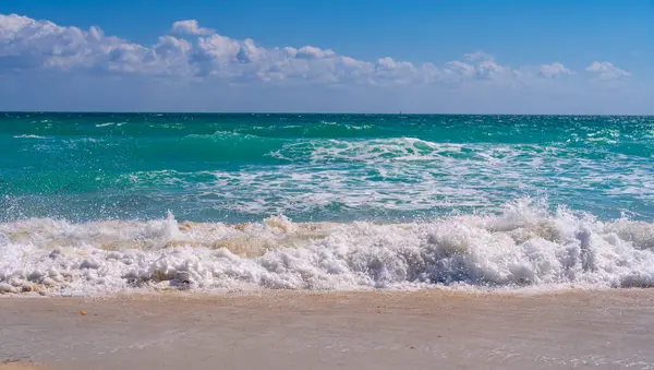 Turkuaz deniz dalgası hareketi. Yaz plajı. Sakin deniz. Lüks sahil beldesi. Parlak gökyüzü ve sahilde dalgalar. Güzel köpüklü kıyı şeridi. Deniz arka planı. Mavi okyanus. Kumlu okyanus plajı. Deniz dalgaları