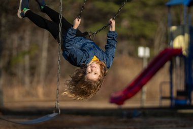 Çocuk salıncakta sallanıyor. Çocuk çocuk çocuk parkında sallanıyor. Parkta sallanan çocuk. Mutlu çocuk dışarıda oynamaktan hoşlanıyor. Sevimli çocuk oyun alanında eğleniyor. Çocuk parkında sallanıyor