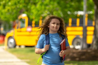 Okul otobüsü dışarıda çocuk öğrenciyi bekliyor. Sırt çantası ve okula gidecek kitapları olan bir çocuk. Devlet okuluna kadar yürüdüm. Amerikan okulunda eğitim, öğrenim ve bilgi kavramı