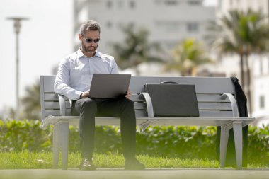 Kendine güveni tam bir iş adamı. Yaz parkında dizüstü bilgisayar ve telefonla bankta oturuyor. Başarı uzaktan yapılan bir iş. Orta yaşlı iş adamı tatilin tadını çıkarıyor. İş adamı bir bankta mola veriyor.