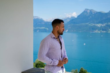 Kaslı bir adam dağ Alpleri manzarasında rahatlar. Alp Gölü 'nde yakışıklı bir turist. Yazın poz veren güçlü, seksi bir adam. Hayalperest, kaygısız bir gezgin. Açık havada insan özgürlüğü