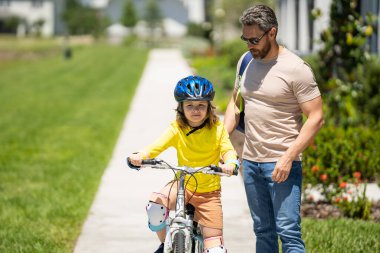 Babalar Günün kutlu olsun. Kask süren bisikletli baba ve oğul. Babasıyla bisiklet süren kasklı, sevimli, beyaz bir çocuk. Aile açık hava yaz aktiviteleri. Çocukluk ve babalık.
