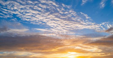 Gün batımında gökyüzü. Gündoğumu arka planı. Gökyüzündeki bulutların arasından gün batımı. Günbatımı renklerinde alacakaranlık gökyüzü. Yumuşak ışıkla huzurlu bir şafak. Bulutlu dramatik alacakaranlık. Açık gökyüzünde gün ışığı