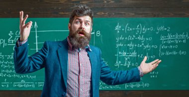 Öğretmen tahtada matematiği açıklıyor. Sınıfta tahtası olan bir öğretmen. Öğretmen matematik formülü yazıyor. Sakallı öğretmen. Profesör sınıfta ders veriyor. Profesör matematiği açıklıyor