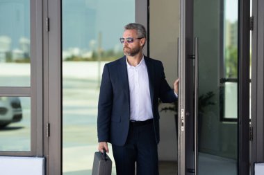 İş adamı bir ofis binasına giriyor. Yetişkin bir iş adamı toplantıya giriyor. Ofis kapısından giren bir iş adamı. Karizmatik iş adamı kapıdan giriyor. İş anlaşması