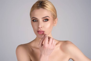 Gorgeous young woman in stylish makeup. Girl posing with new lipstick in studio. Sexy girl rouging her lips. Sexy model holding red lipstick. Applying lipstick cream balm to mouth. Red is trending