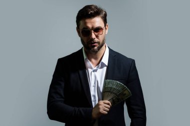 Üzerinde nakit para banknotları olan tişörtlü bir iş adamı sarı stüdyo geçmişinden izole edilmiş. 100 dolarlık banknot, finansal konsept.