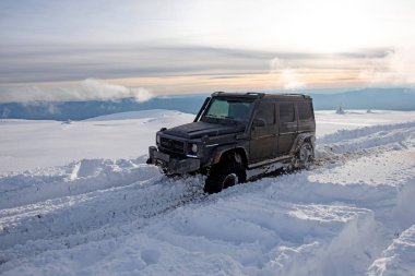 01.02.2021, Karpatlar. Gün batımında kar içinde off-road SUV. 4x4 jipli bir kış seferi. Kış doğasında zorlu bir off-road gezisi. Kış off-road. Kar yolunda macera gezisi. Kış yolları