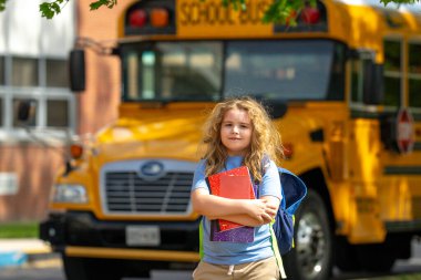 Okula dönelim. Genç öğrenciler için okul başlıyor. Okul otobüsünün yanında sırt çantalı bir çocuk. Çocuk okula gidiyor. Çocuk derse gidiyor. Okul çocuğu.