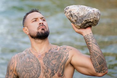 Doğada güçlü bir adam. Şelalenin altına sıçrayan seksi üstsüz adam. Formda ve güçlü bir erkek vücudu. Seksi manken yazın tadını çıkarıyor. Erkek güzeli. Gövdesi su damlayan kaslı bir adam.