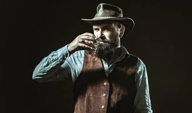 Sakallı adamın tuttuğu konyak bardağı. Barda yalnız başına konyak içen adam. Klasik bardakta viski konyağı. Konyak retro tarzında tatmak. Pahalı viski. Viski konsepti iç. Alkolik içecek.