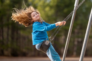 Çocuk salıncakta eğleniyor. Çocuk bahçesinde mutlu bir çocuk. Havada sallanan kaygısız çocuk. Mutlu çocuklar dışarıda oynuyor. Sarışın çocuk heyecandan titriyor. Dışarıdaki oyuncu çocuk. Komik çocuk suratı