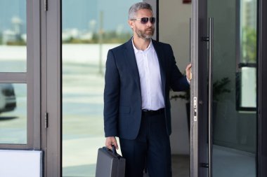 İş adamı bir ofis binasına giriyor. Yetişkin bir iş adamı toplantıya giriyor. İş adamı ofis kapısından içeri giriyor. Karizmatik iş adamı kapıdan giriyor. İş anlaşması