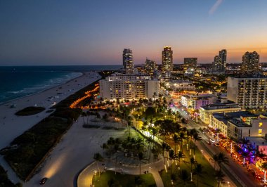 Miami Sahili Günbatımı hava manzarası. Alacakaranlıkta Miami 'nin göbeğinde. Güney Sahili neon ışıkları. Tropik Miami kıyısı manzarası. Ocean Drive Art Deco binaları. Miami kıyı şeridinin havadan görüntüsü