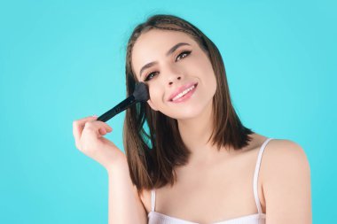 Woman applying foundation powder or blush with makeup brush. Facial treatment, perfect skin, natural make up, facial beauty. Isolated on studio background. Applying makeup
