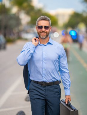 İş adamı şehirde güvenle yürüyor. Sokakta yürüyen bir iş adamı. Ofise doğru yürüyen yakışıklı bir iş adamı. Kendine güvenen girişimci iş adamı dışarıda yürüyor.