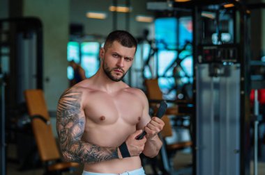 Spor salonunda egzersiz yapan güçlü bir genç adam. Spor kulübünde spor erkek antrenmanı. Genç adamın fitness antrenmanı var. Erkek sporcu egzersiz, spor ve antrenman yapar. İnsanlar spor ve sağlıklı yaşam tarzları