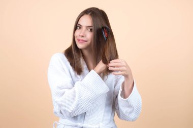 Young woman combing hair. Beautiful woman brush healthy hairs. Hairstyle and haircare concept. Girl combing and brushing hair in studio. Woman with comb combing hair. Hair brush