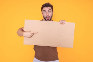 Adamın elinde işaret var, boş kart. Ürününüz için pankart hazır. Stüdyonun arka planında boş tabela gösteren bir adam var. Boş tahta var. Reklam alanı, kopyalama alanı