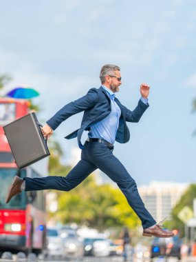 İş atlayışı. Caddeye atlayan çılgın bir iş adamı. Takım elbiseli bir işadamı geç kaldı ve atladı. Sıçrama hareketiyle meşgul bir iş adamı. Kendine güvenen işadamı heyecanla zıplıyor.
