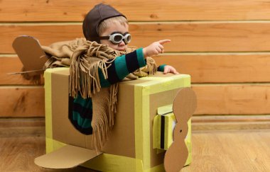 Karton kanatlı uçan bir çocuk. Çocuk pilotluk hayali kuruyor. Kağıt uçakla bebek uçuşu. Havacı kasklı çocuk içeride. Oyuncak uçakla uçan çocuk. Hayalci çocuk karton kutuda uçuyor.