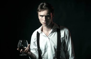 Ciddi bir adamın elindeki brendi bardağı. Barda tek başına brendi içen adam. Klasik klasik bardakta konyak konyağı. Brendi viskisi retro tarzında. İçki konsepti