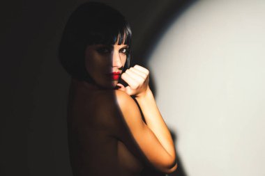 Genç, çıplak, seksi bir kadının şehvetli portresi. Stüdyo gölgesinde poz veren seksi manken. Güzellik kraliçesinin moda çekimi. Moda makyajlı seksi manken. Seksi esmer kadın.