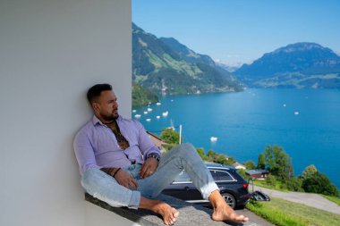 Kaslı bir adam dağ Alpleri manzarasında rahatlar. Alp Gölü 'nde yakışıklı bir turist. Yazın poz veren güçlü, seksi bir adam. Hayalperest, kaygısız bir gezgin. Açık havada insan özgürlüğü