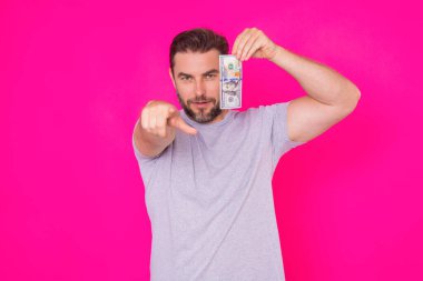 Orta yaşlı İspanyol adam, izole edilmiş pembe arka planda nakit para tutuyor. Dolar banknotları olan bir iş adamının stüdyo portresi. Dolar parası konsepti. Kariyer zenginliği işi