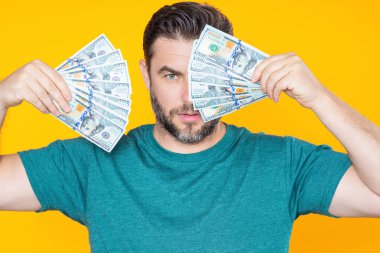 Adam sarı stüdyonun arka planına para koydu. Dolar banknotları olan zengin adamın portresi. Dolar banknotları olan başarılı bir adam. Zengin milyoner.