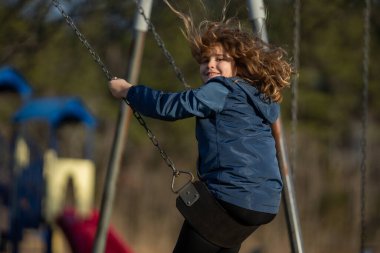 Çocuk salıncakta sallanıyor. Çocuk çocuk çocuk parkında sallanıyor. Parkta sallanan çocuk. Mutlu çocuk dışarıda oynamaktan hoşlanıyor. Sevimli çocuk oyun alanında eğleniyor. Çocuk parkında sallanıyor