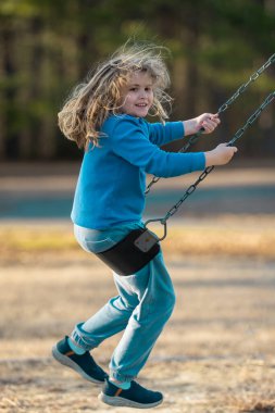 Heyecanlı çocuk eğleniyor. Çocuk bahçesinde mutlu bir çocuk. Havada sallanan kaygısız çocuk. Mutlu çocuklar dışarıda oynuyor. Sarışın çocuk heyecandan titriyor. Dışarıdaki oyuncu çocuk. Komik çocuk suratı