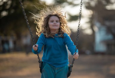 Çocuk salıncakta eğleniyor. Çocuk bahçesinde mutlu bir çocuk. Havada sallanan kaygısız çocuk. Mutlu çocuklar dışarıda oynuyor. Sarışın çocuk heyecandan titriyor. Dışarıdaki oyuncu çocuk. Komik çocuk suratı