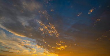 Gün batımında gökyüzü. Ufukta gün doğumu. Güneş ışığı bulutların arasından gökyüzünde parlıyor. Alacakaranlık gökyüzü canlı renklerle. Yumuşak ışıkla huzurlu bir şafak. Parlayan bulutlarla dramatik alacakaranlık. Açık gökyüzünde gün ışığı